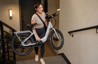 Petite woman carrying lightweight e-bike up apartment stairs