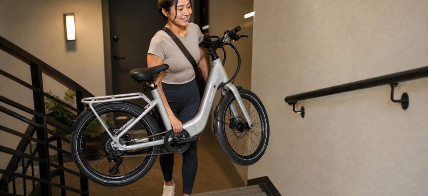 Petite woman carrying lightweight e-bike up apartment stairs
